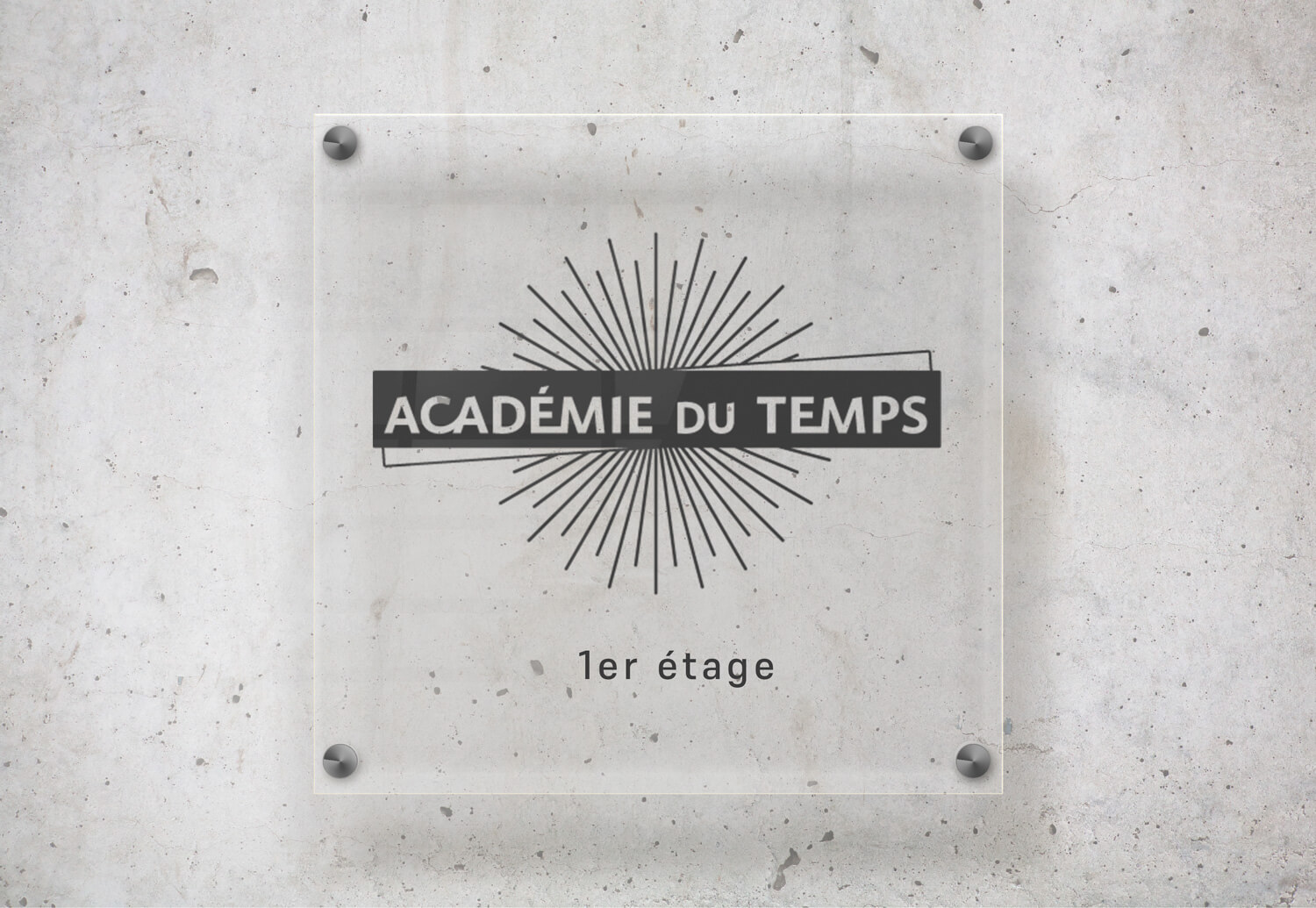 Plaque signalétique en plexiglas fixée sur un mur béton avec le logo “Académie du Temps” réalisé par Gaële Gerbaux – Studio nueva vista, design professionnel en situation réelle.