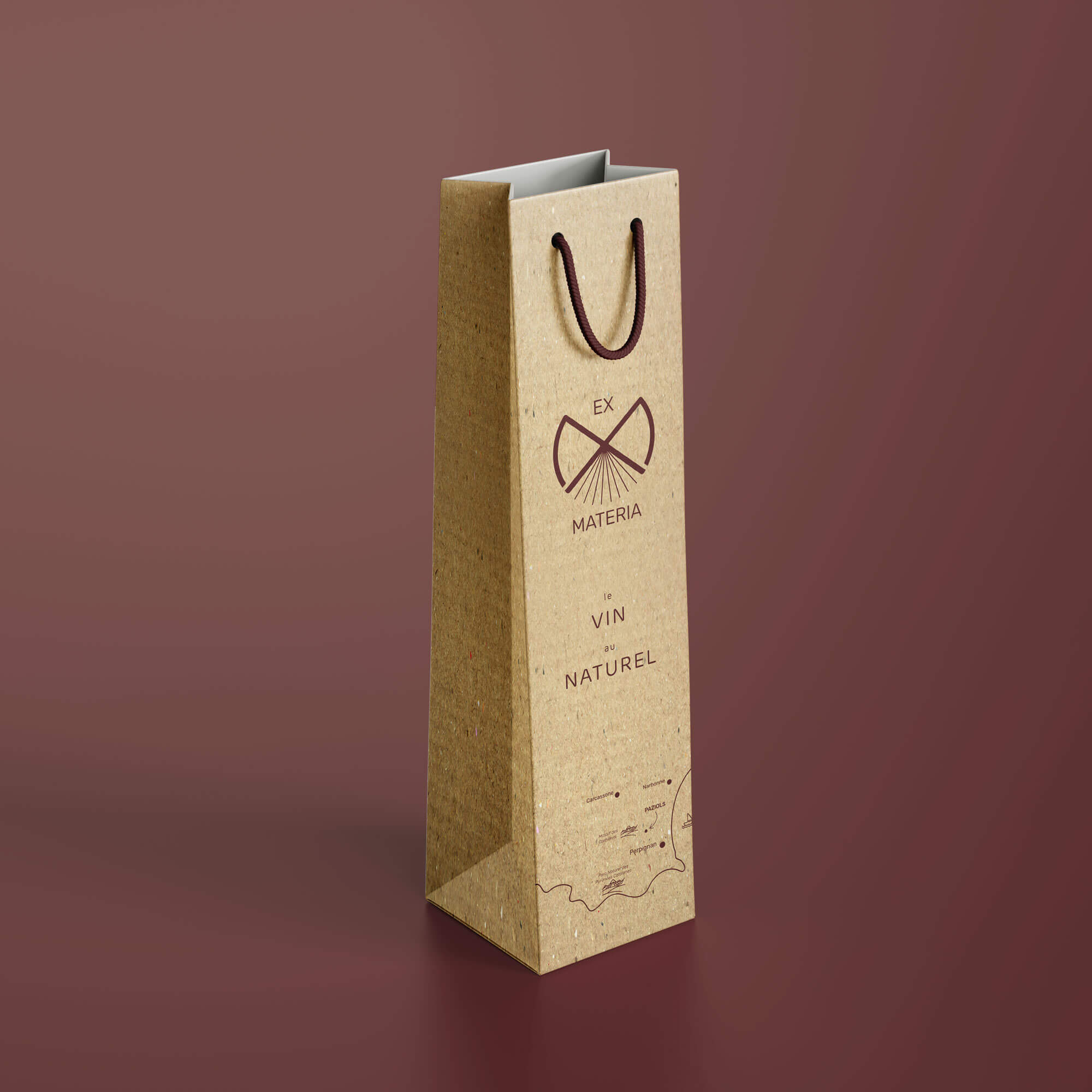 Mockup d’un sac kraft pour bouteille de vin, présentant le logo “Ex Materia” conçu par Gaële Gerbaux du studio nueva vista : motif symbolique en brun, typographie élégante et mention “vin naturel”, avec illustration cartographique stylisée en bas du sac, sur fond bordeaux.