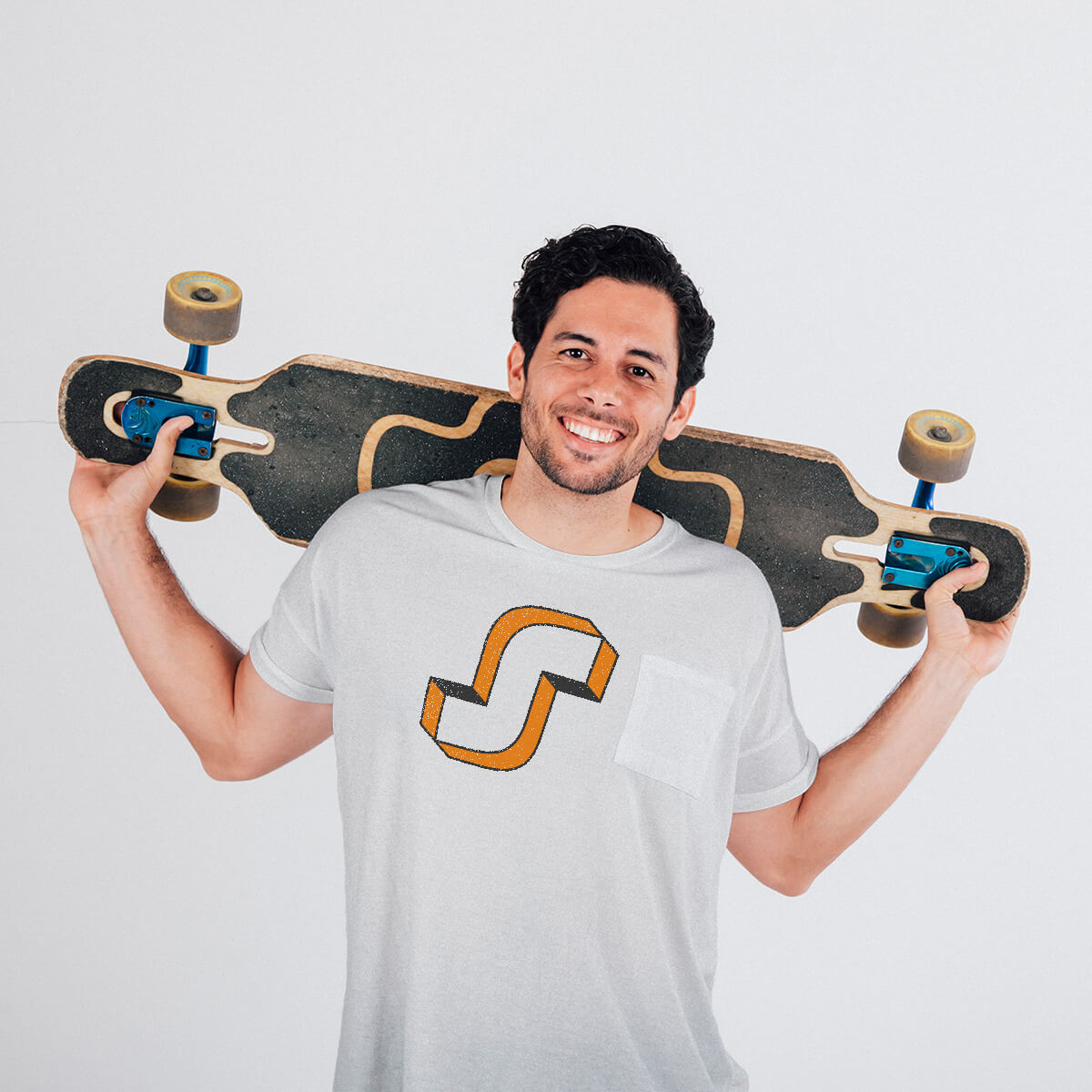 Mockup photo d’un homme souriant portant un t-shirt blanc affichant le logo “System” conçu par Gaële Gerbaux – Studio nueva vista. Il tient un longboard sur les épaules, dans une mise en situation destinée à valoriser le design du logo pour une marque spécialisée dans les espaces de sports urbains.